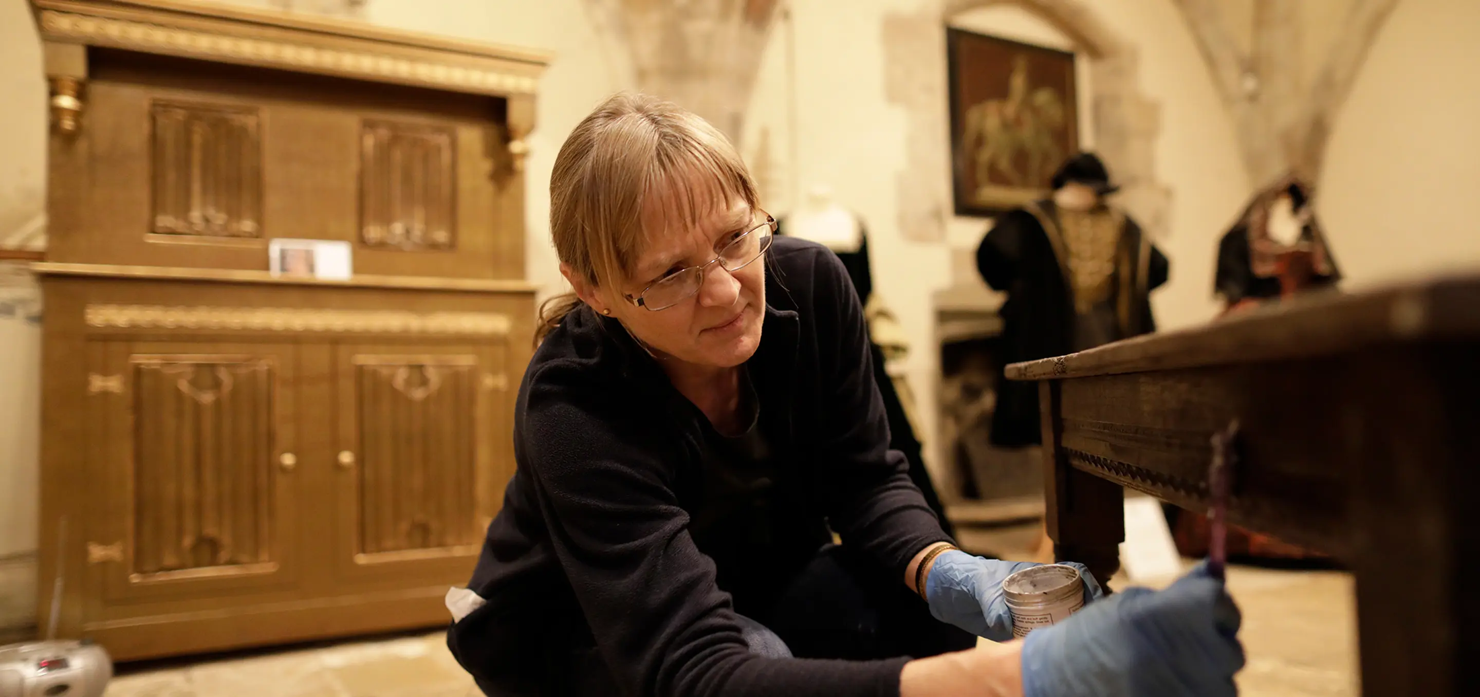 Woman restoring a piece of furniture in a historic house